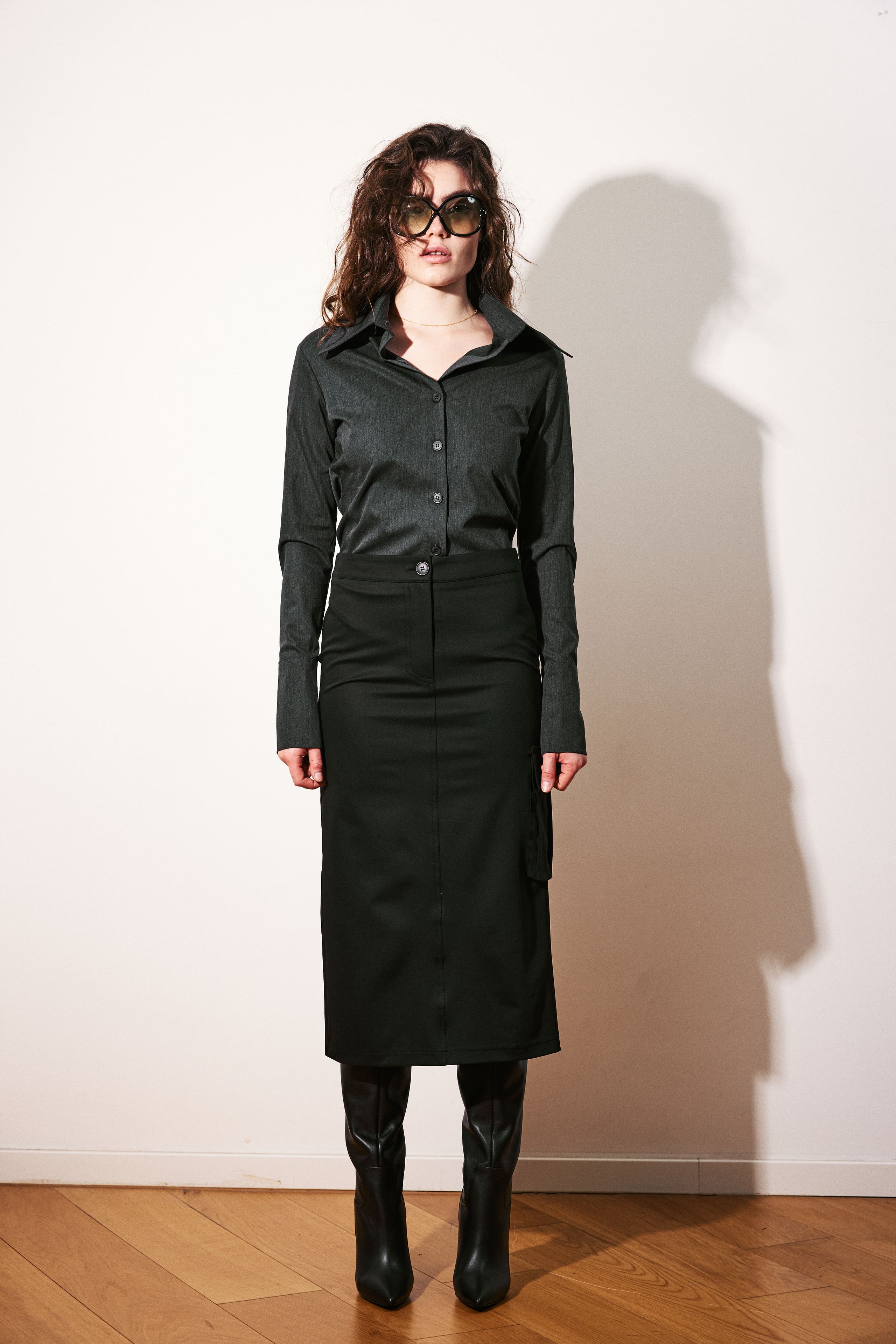 A charcoal shirt tucked into a black cargo midi skirt under hard flash for AGIC's lookbook.