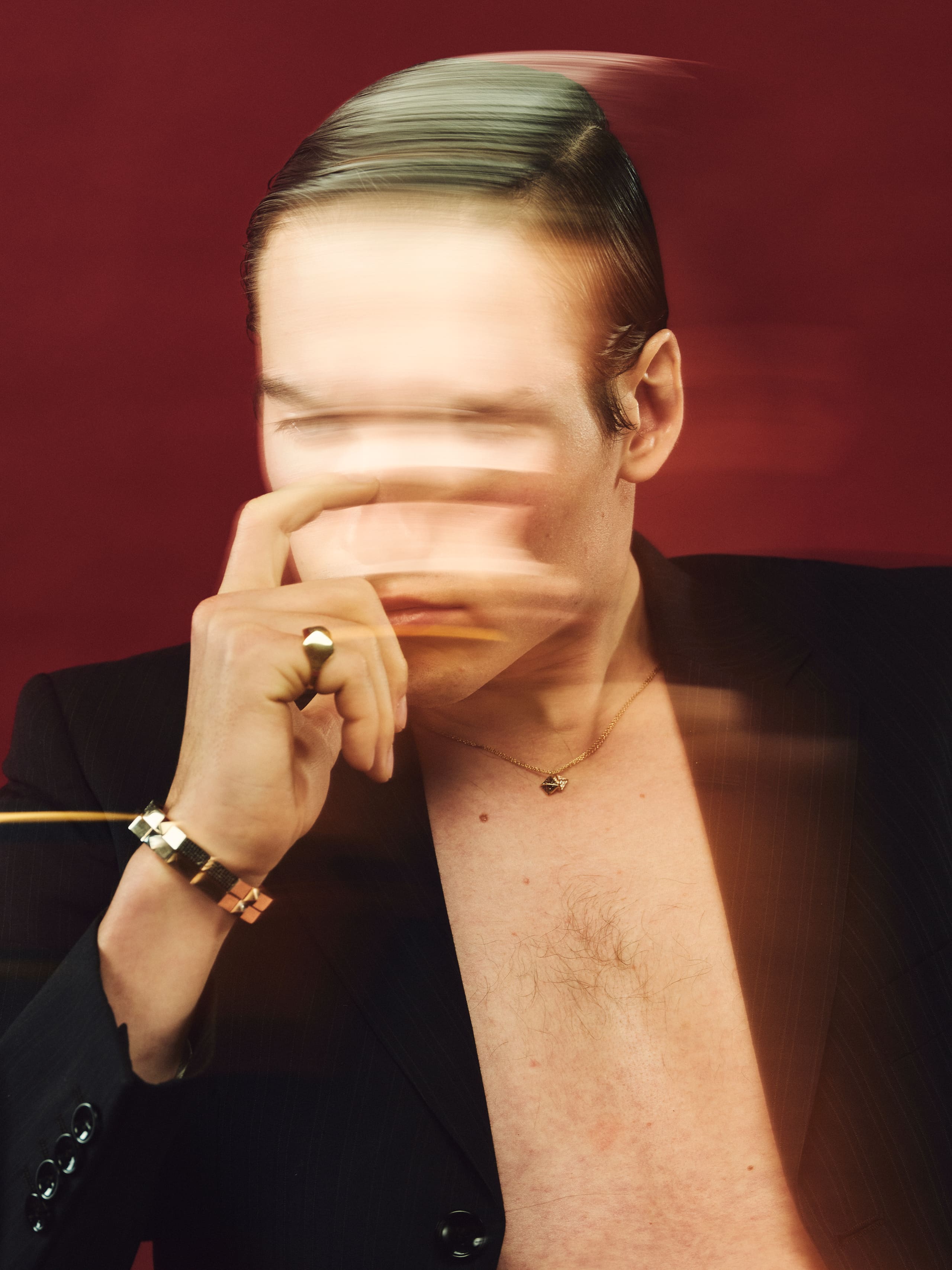 A finger crosses blurred lips while the gold cube bracelet and Dime Tribe pendant hold focus on red.
