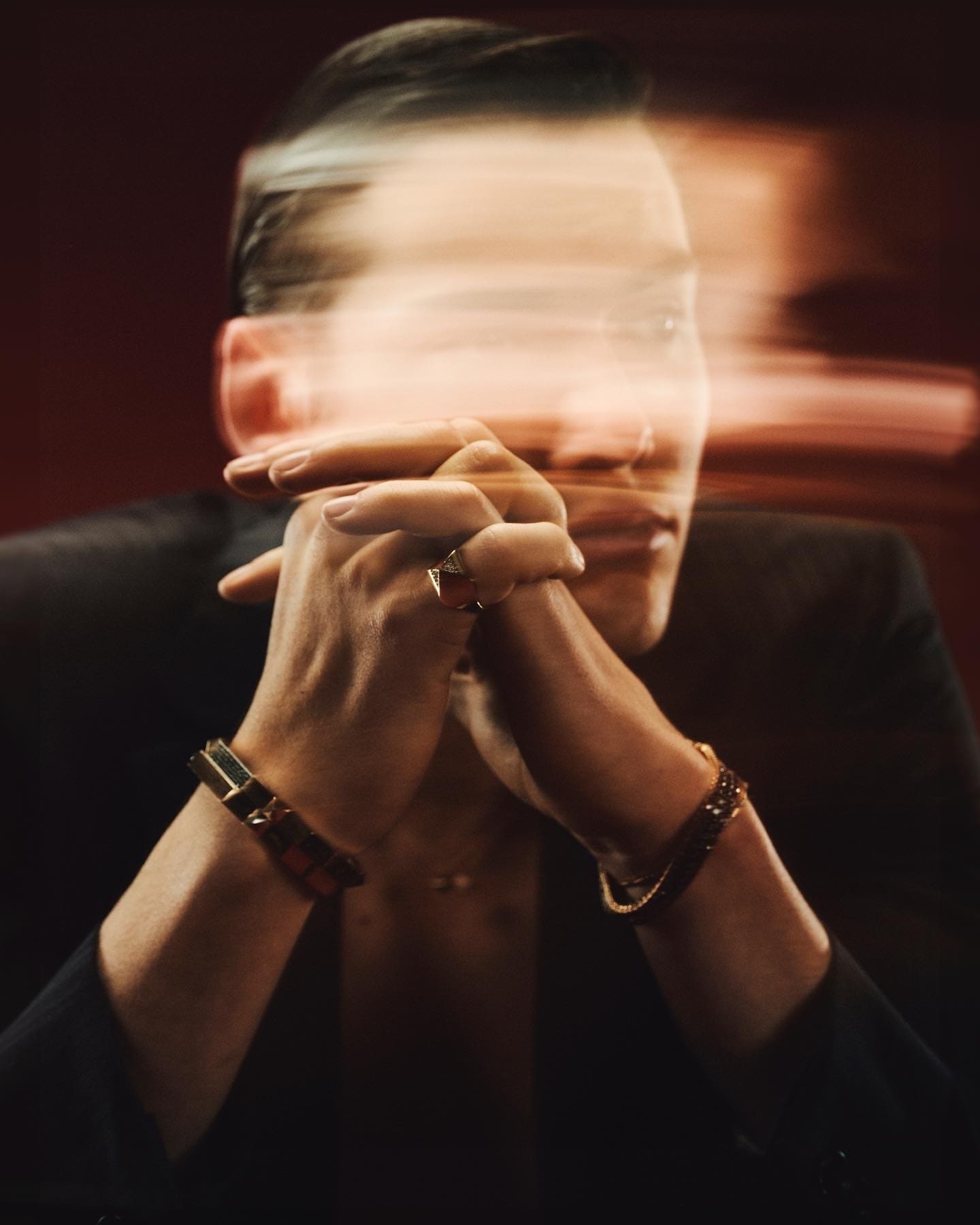 The gaze survives inside a horizontal smear of light, clasped hands and Dime Tribe gold anchoring the frame.