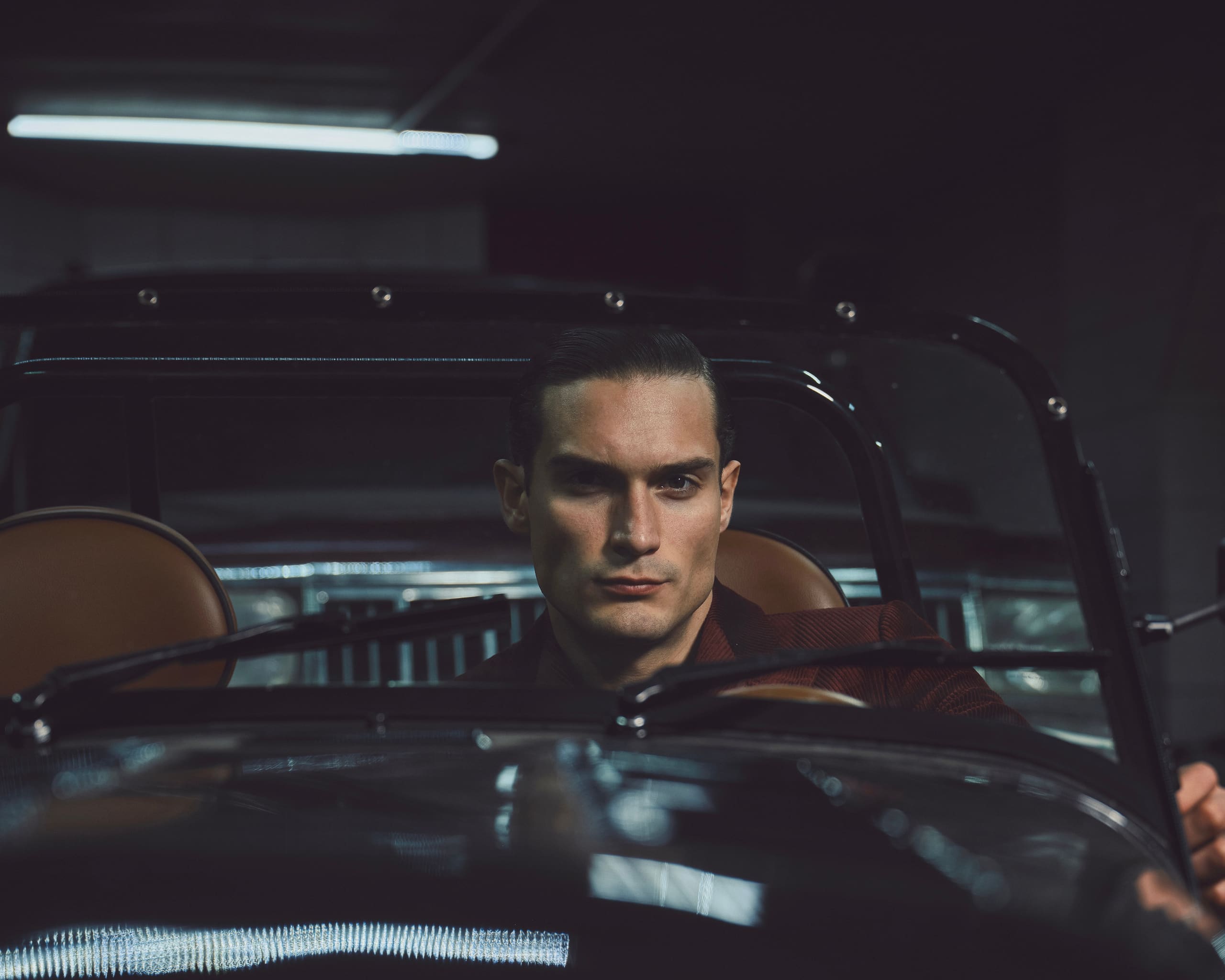 A slicked-back driver holds a level stare through the split windshield of a vintage roadster in Dime Tribe's Rocky Road campaign.