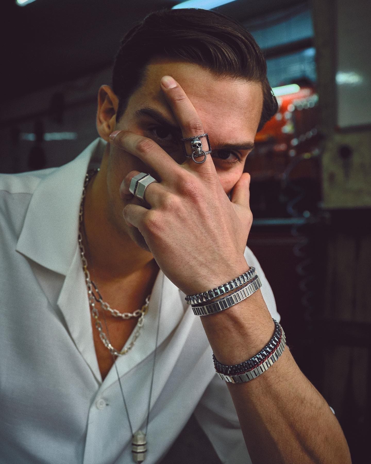 Skull and hexagon rings splay across the model's face in a tight Dime Tribe close-up, bracelet stacks lining both wrists.