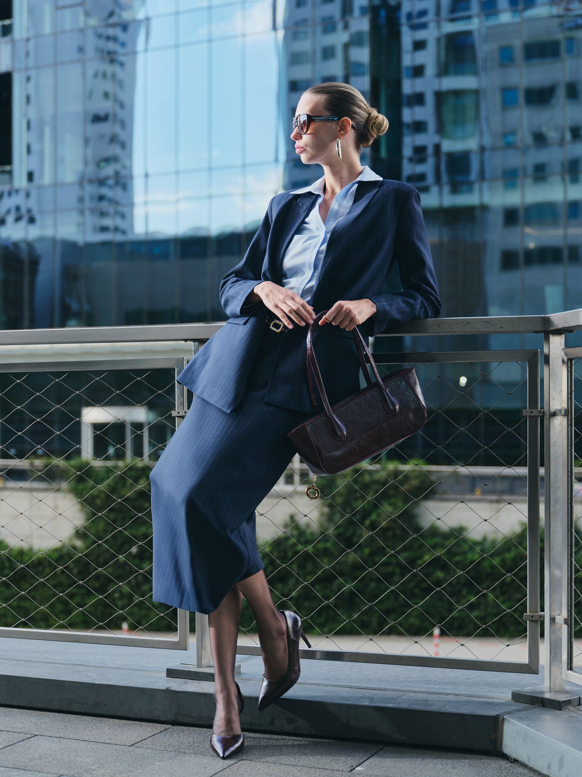 Leaning back into the railing with the burgundy bag dangling, chin turned to the skyline for LC Waikiki