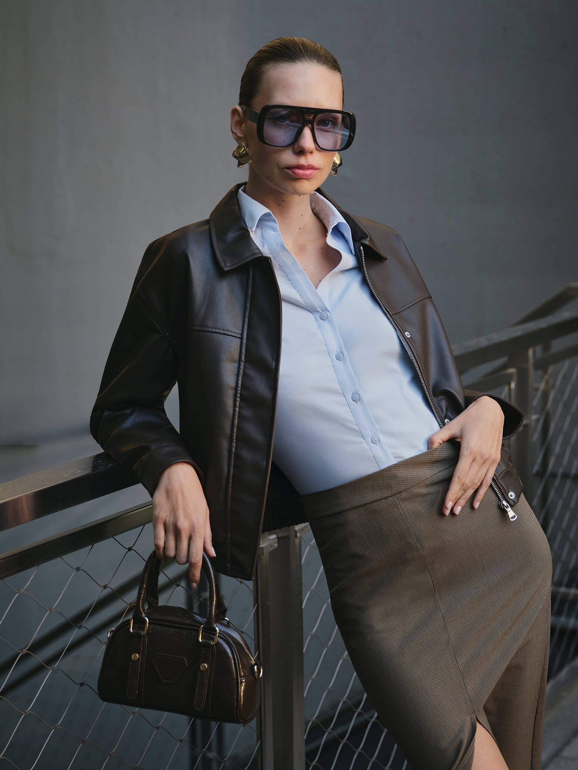 Close at the railing in oversized shield frames and gold earrings, the bomber's zip open over powder blue for LC Waikiki