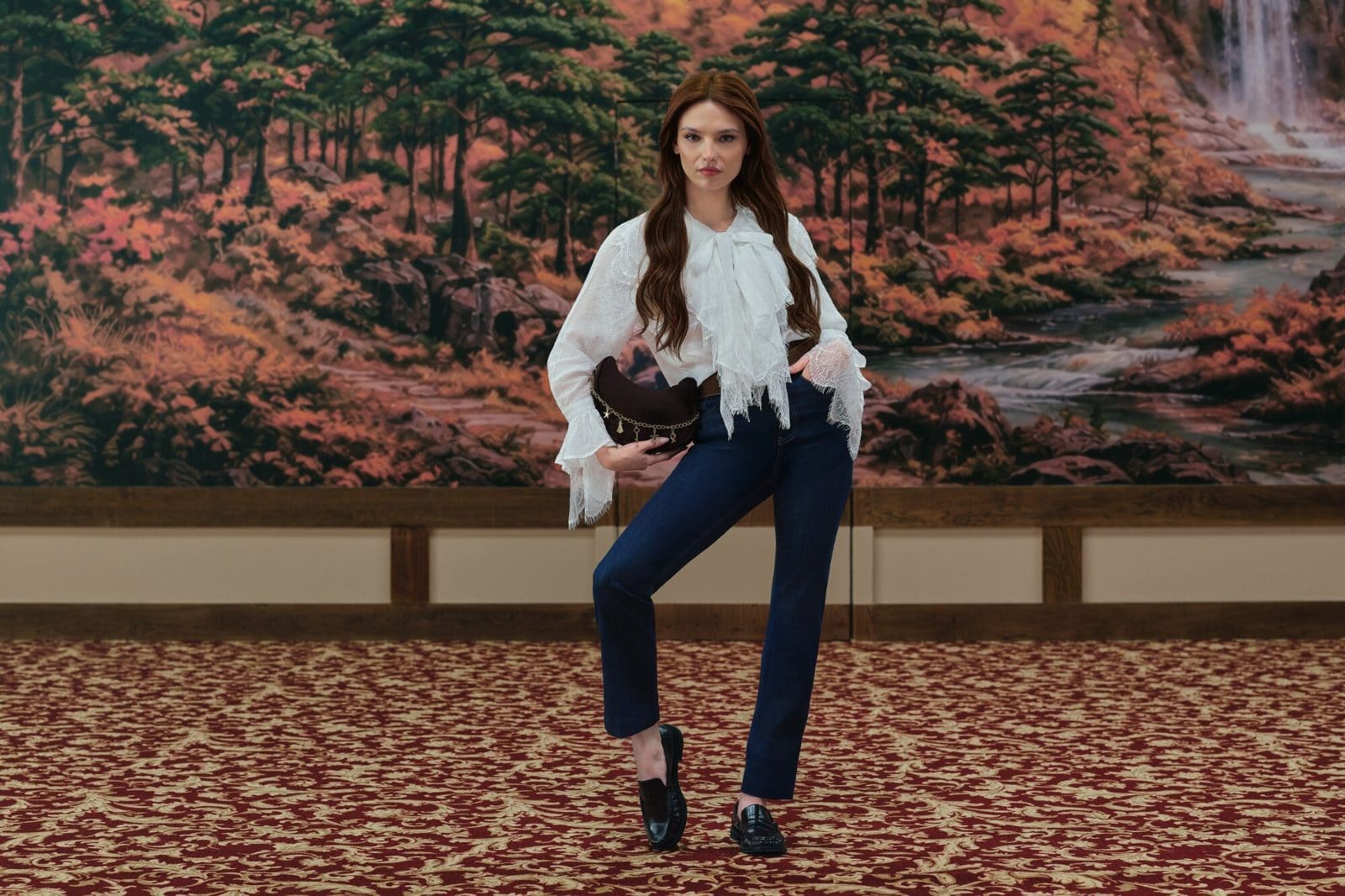 Nilsu Berfin Aktaş pairs a lace-trimmed white blouse with indigo denim in front of a kitsch forest mural for LC Waikiki.