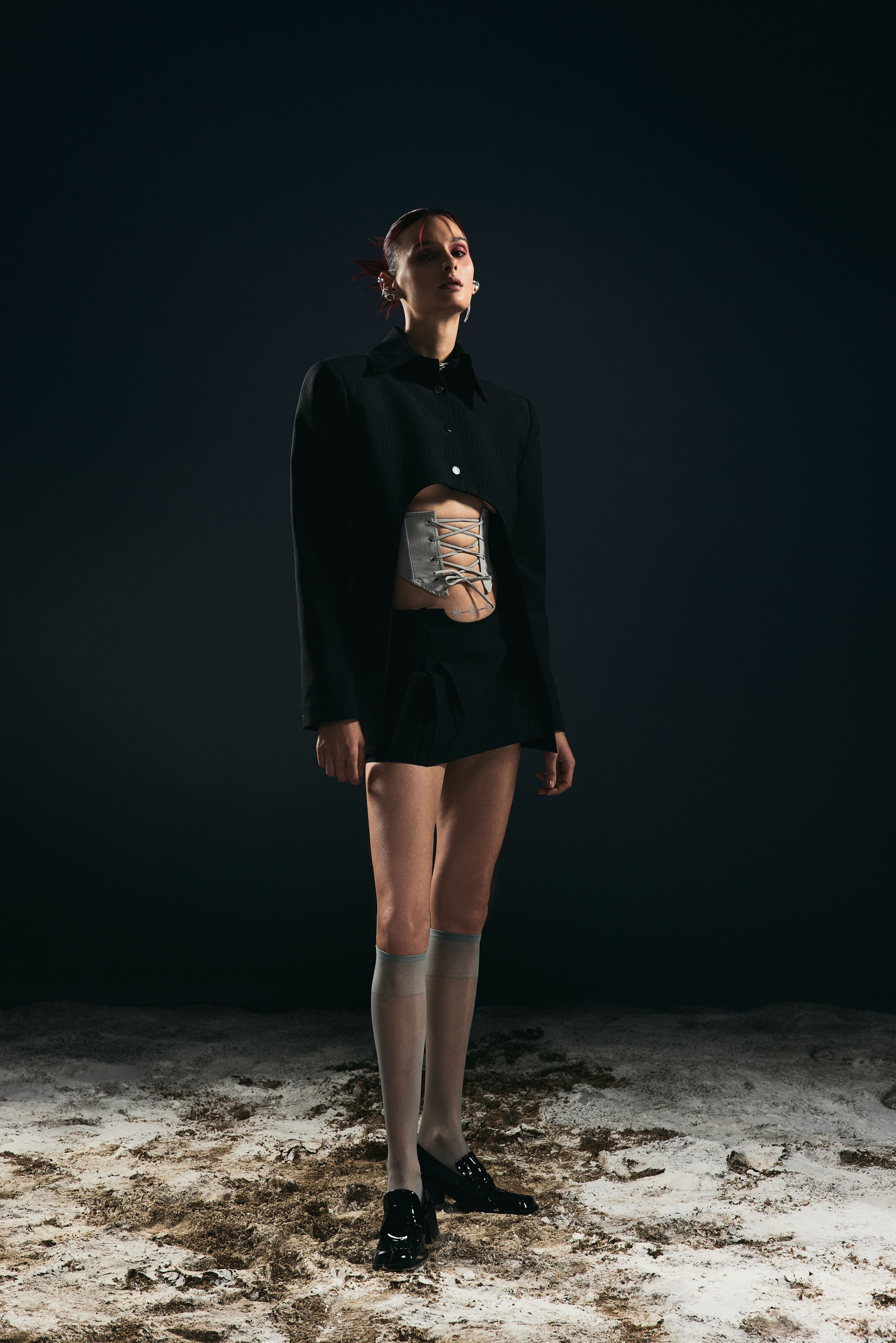 Sheer knee socks and patent loafers ground the pinstripe blazer and laced corset in Mysamoon's full-length uniform study.