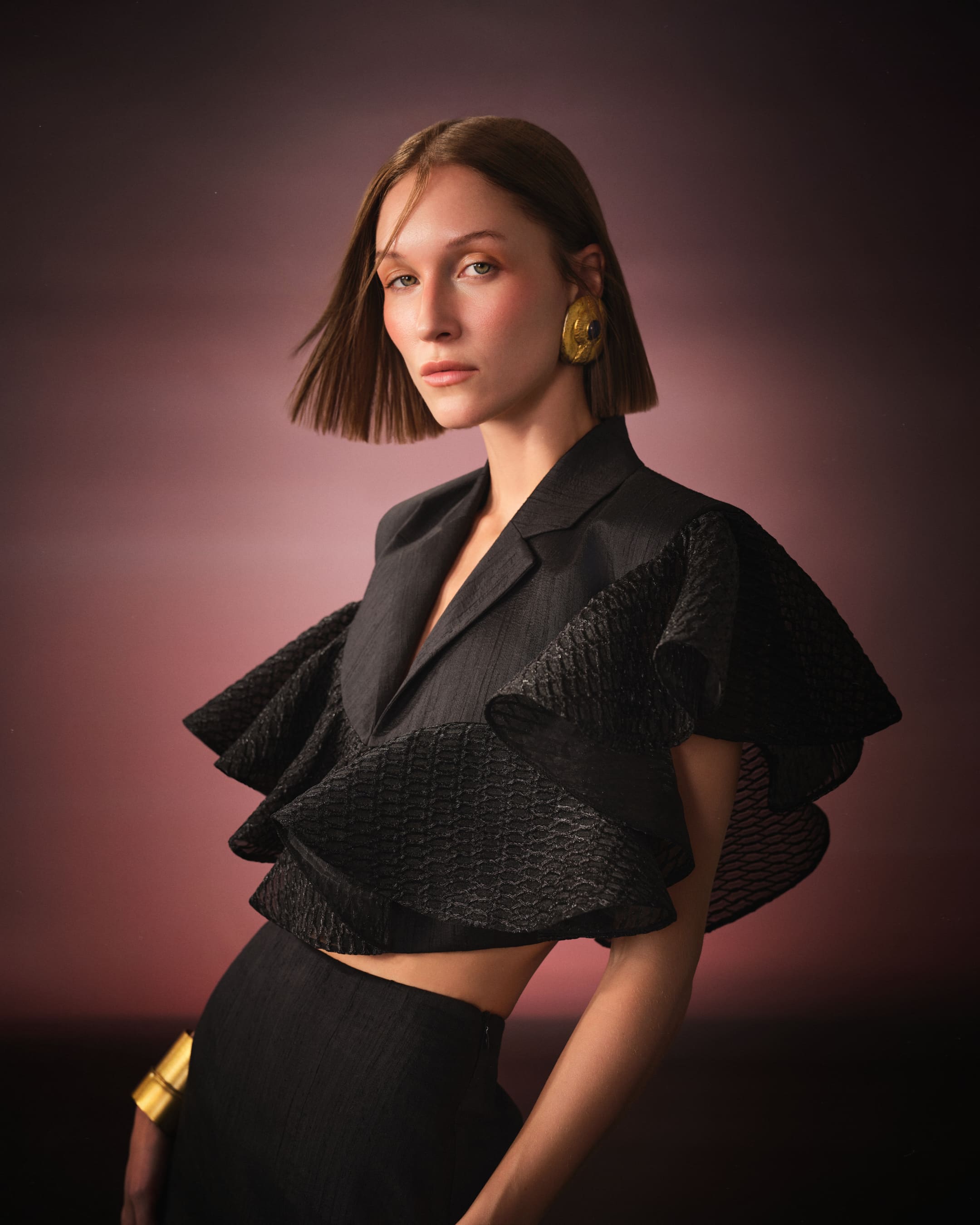 A cropped black blazer erupting into lattice ruffles under rose-toned cosmic haze for Saint Ones.